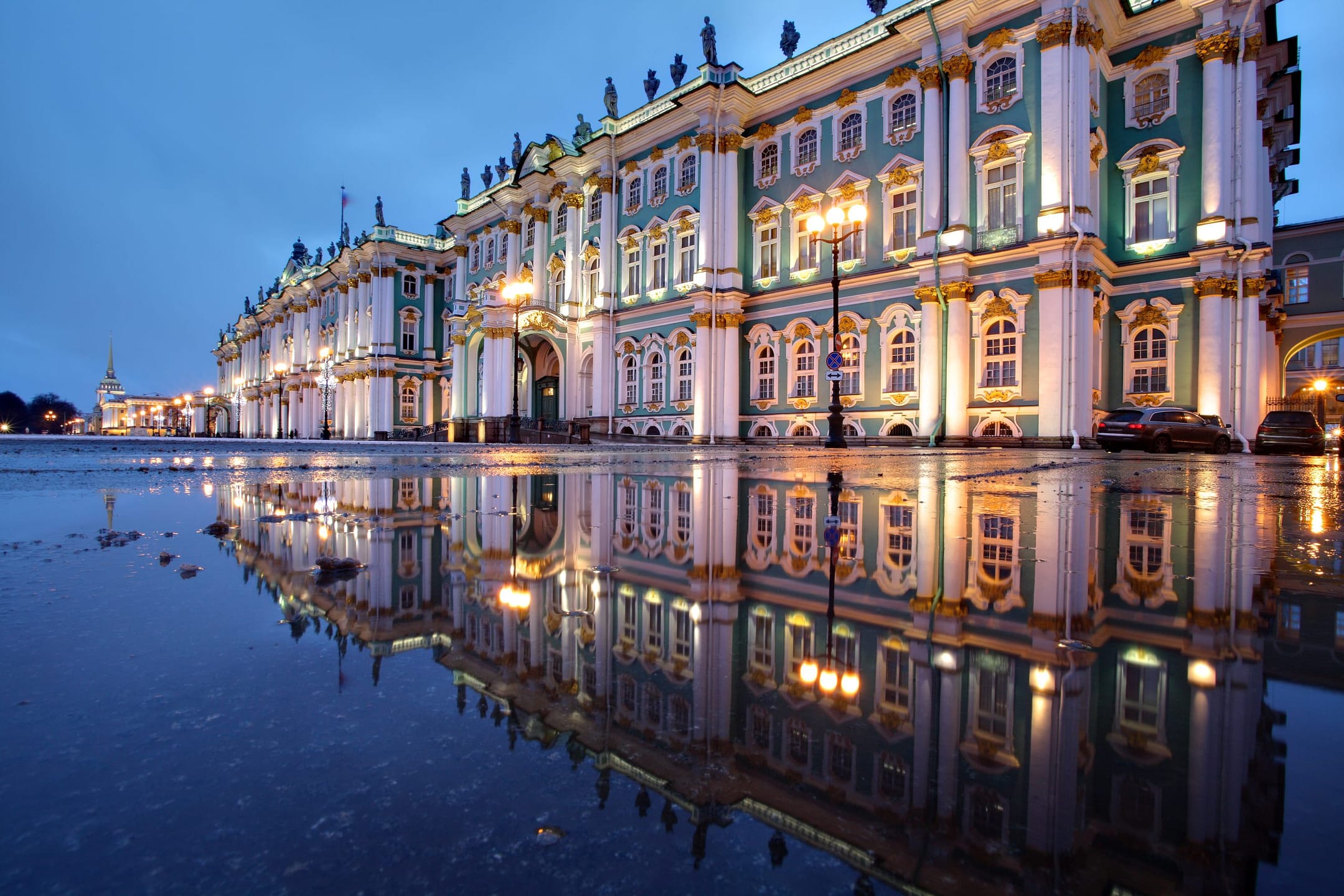 Illuminated historic building with reflection in water.