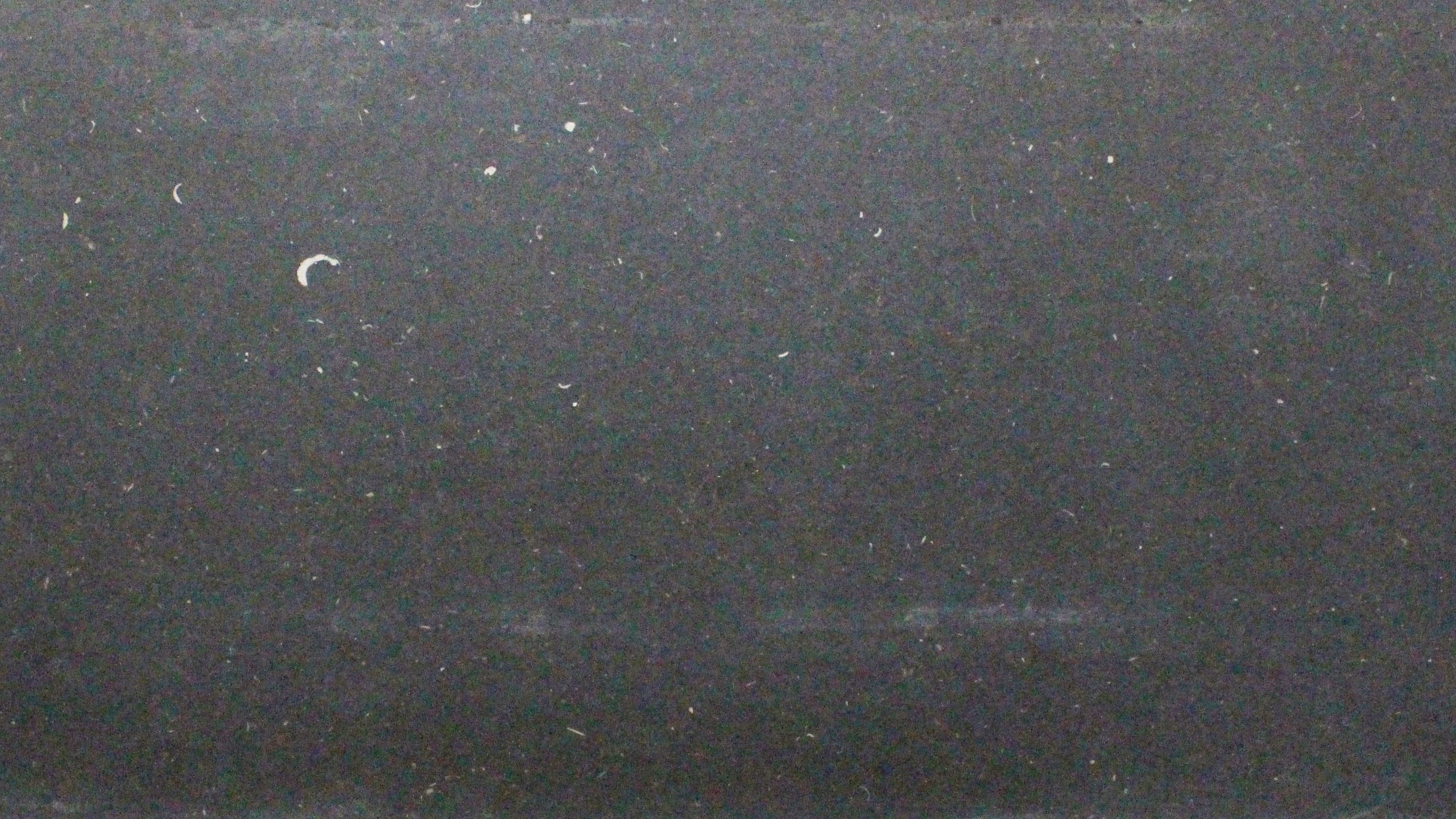 Black grainy texture with scattered white speckles.