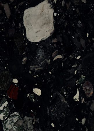 Dark textured rock surface with various stones.