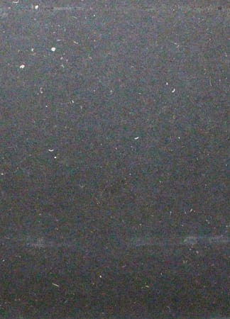 Black grainy texture with scattered white speckles.