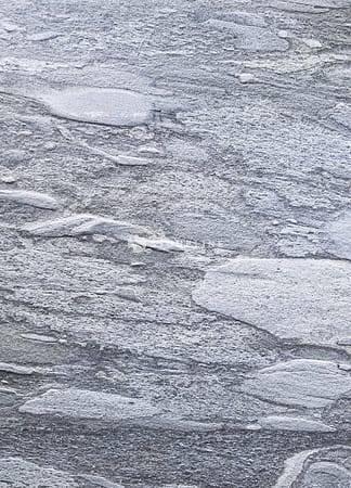 Gray textured stone surface with uneven patterns.