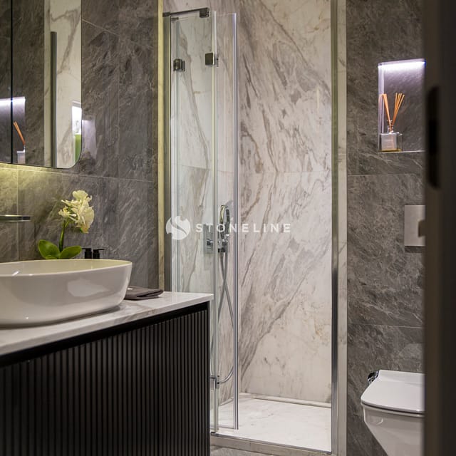 Modern marble bathroom with shower and vanity.