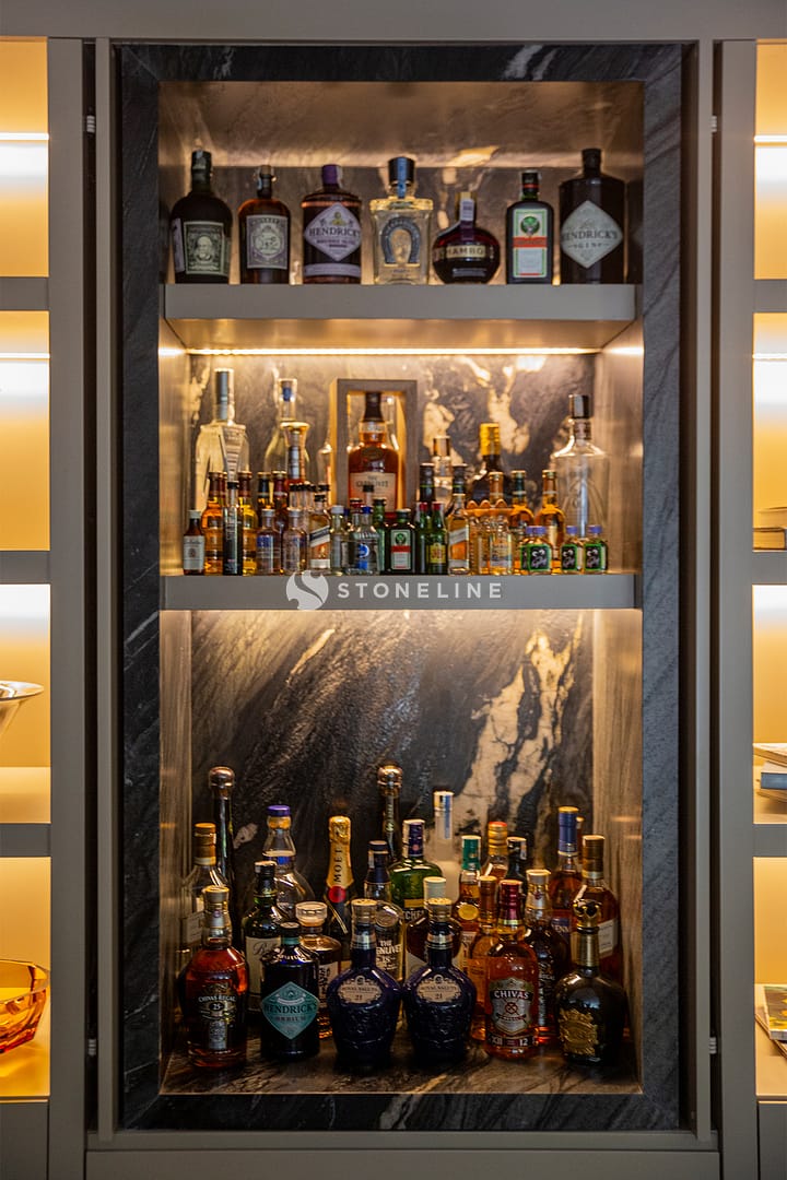 Illuminated liquor cabinet with various bottles on display.