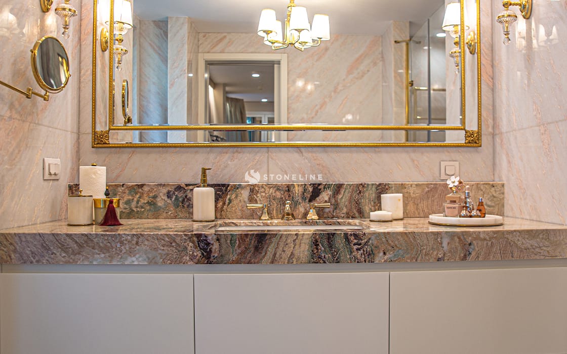 Luxurious bathroom with marble sink and gold mirror.