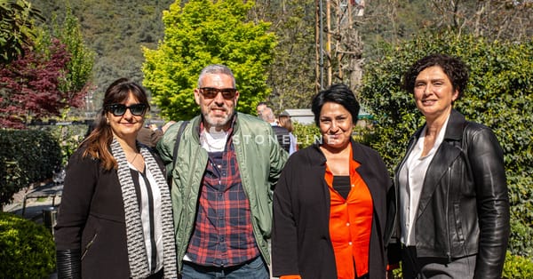 Group of four people smiling outdoors in sunshine.