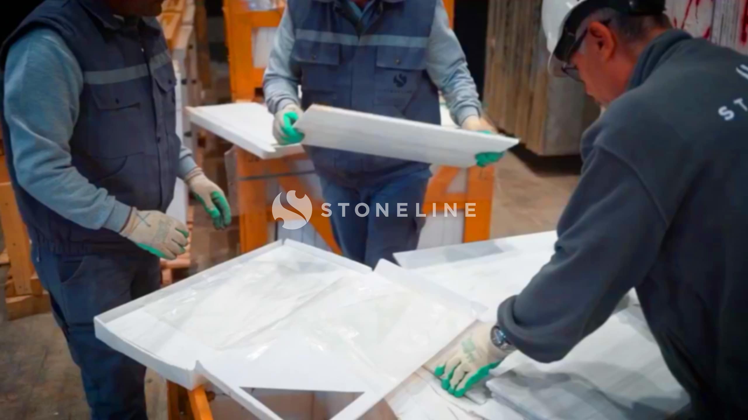 Workers assembling white panels in a factory.